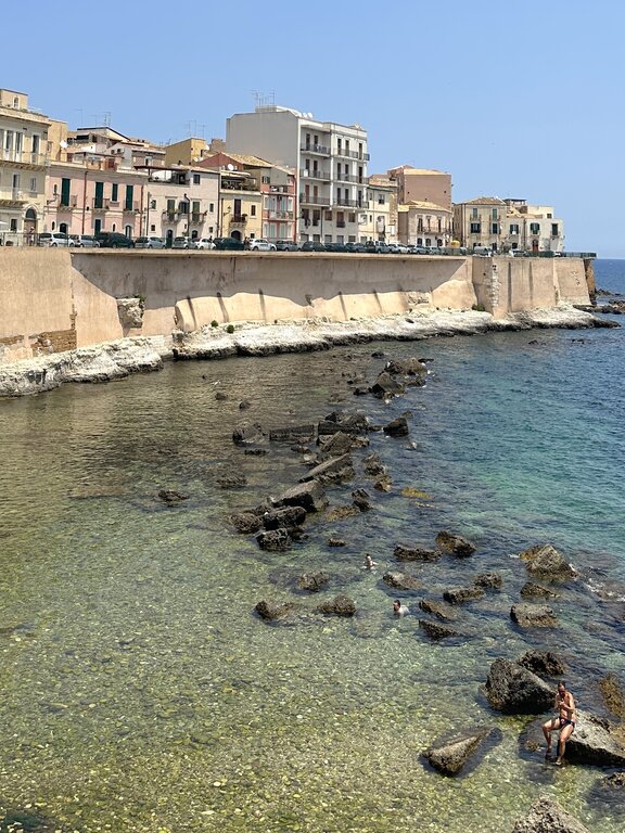 People swimming in the sea from Spiaggia di Cala Rossa Beach in Ortigia - what to see in Syracuse Sicily in 1 day