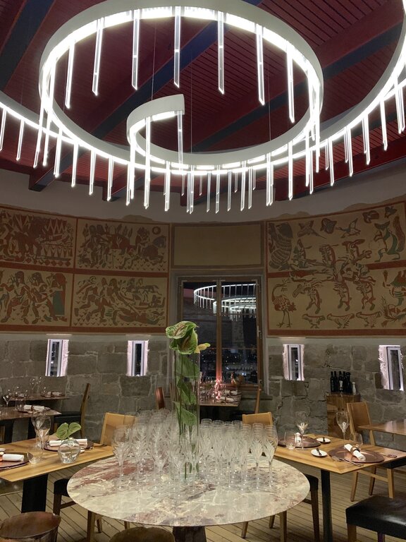 Tables and chairs set for dinner at Strelec Restaurant inside Ljubljana Castle, with historic motifs on the walls, Slovenia