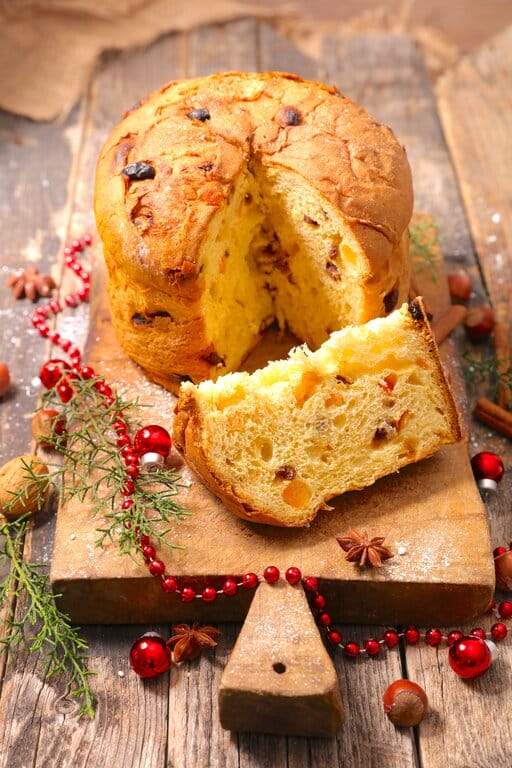 A whole panettone and a slice on a wooden board