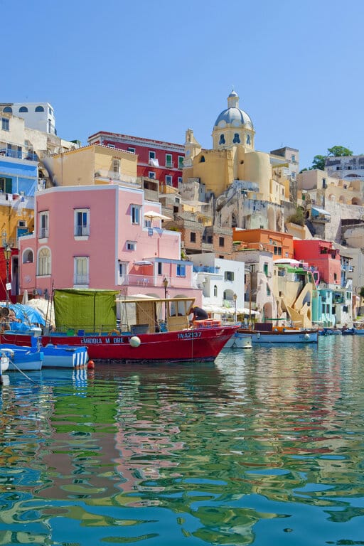 Boats on the water with colorful buildings in the background in Procida islands, Naples