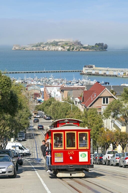 A cable car in San Francisco and Alcatraz Island in the background