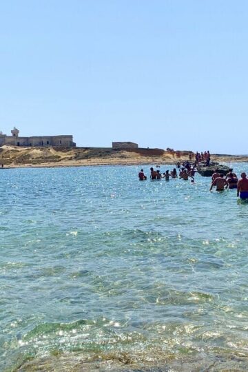 People walking to Isola delle Correnti in Sicily - beautiful islands where Italians vacation