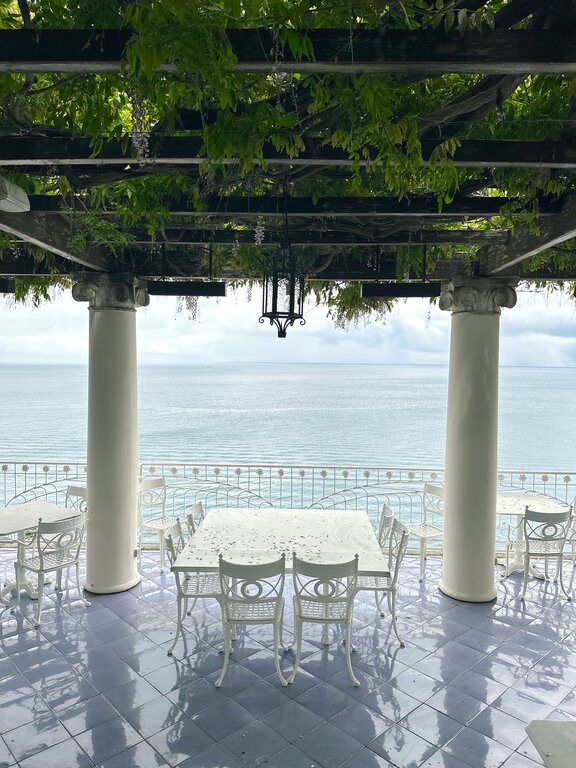 Outdoor tables and chairs beneath a green leafy canopy at Hotel Bellevue Syrene in Sorrento, Italy