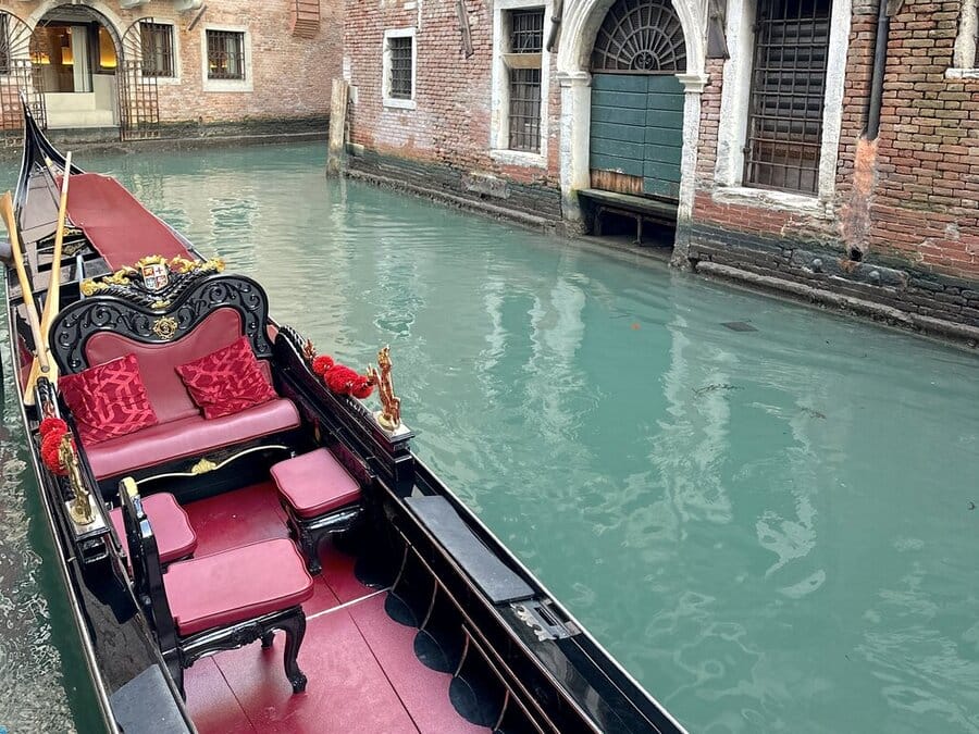 A black gondola with red cushions and lining in Venice Italy — hotels near Venice Airport