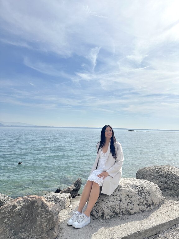 Lisa Rivera sitting by the beach in Sirmione Lake Garda
