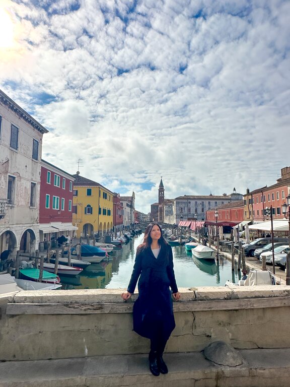 Lisa Rivera sitting on a bridge in Chioggia Venice in February - what to wear in Italy in February