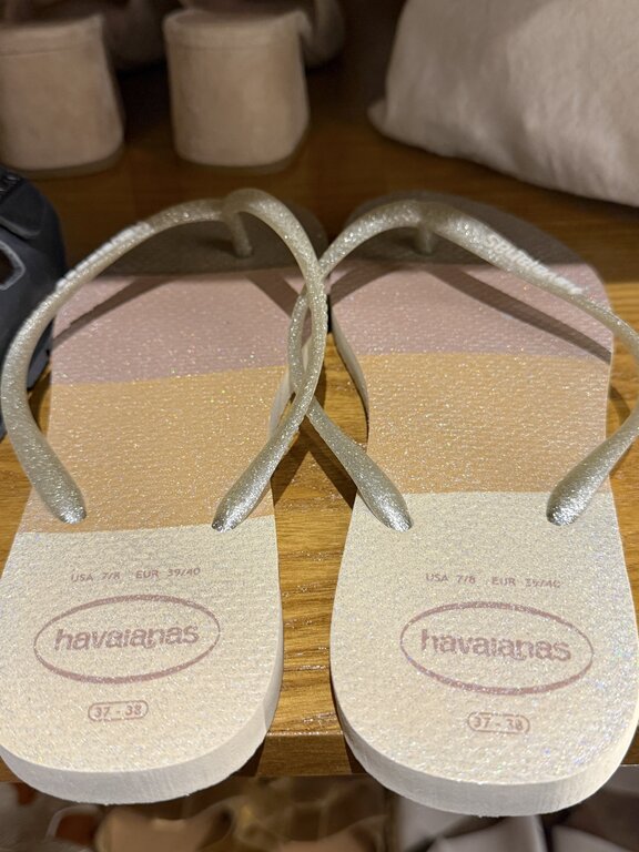 Close-up detail of gold Havaianas flip flops, Italy beach bag and footwear essentials