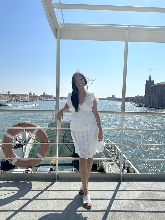Lisa Rivera on the ferry to Lido di Venezia wearing a knee-length white dress and white sandals, what to wear in Venice in summer