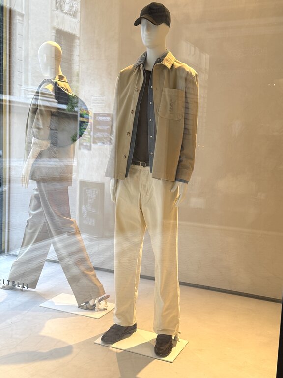 Men's casual Italy outfit: light beige jacket, denim shirt, cream jeans and brown loafers in an Italian shop window. Photo taken by Lisa Rivera