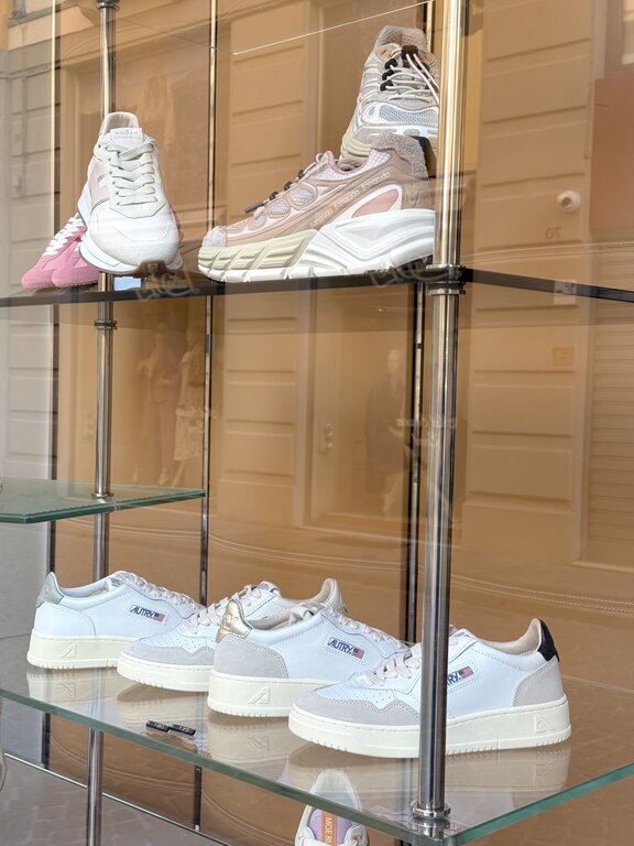 Selection of women's white sneakers from different brands displayed in an Italian shop window. Photo taken by Lisa Rivera