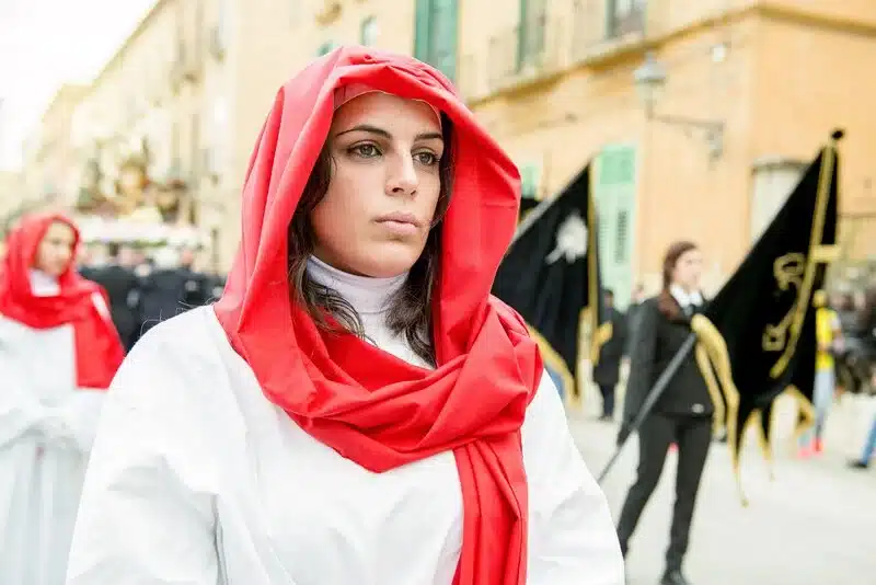 A woman wearing a traditional red lace veil participating in the 24-hour Processione dei Misteri on Good Friday in Trapani, Sicily