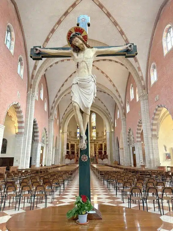 A close-up of a hand-carved wooden statue of Jesus Christ on the cross, representing the solemnity of Good Friday and the Italian tradition of the Descenso